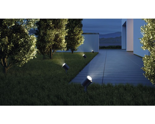 Gartenansicht mit Rasenfläche, Bäumen und mehreren Bodeneinbaustrahlern zur Beleuchtung eines Hauses