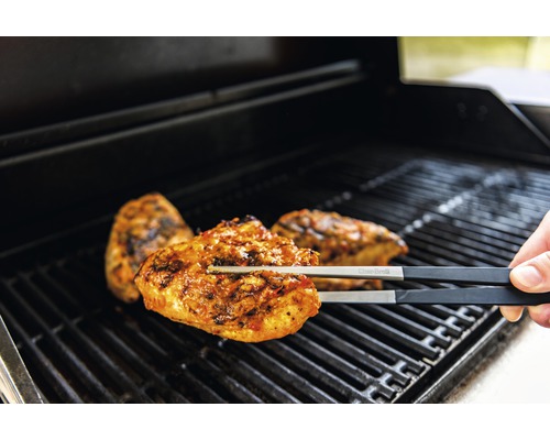 Grillzange hält Hähnchenfleisch auf dem Grillrost