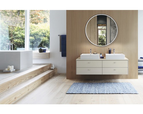 Badezimmer mit Doppelwaschtisch, Spiegel mit Beleuchtung und Badewanne auf einer erhöhten Ebene