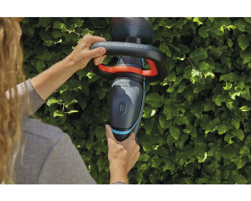 Person bedient eine Gardena Akku-Heckenschere an einer Hecke
