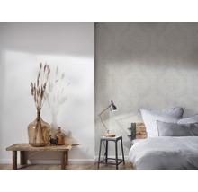 Helles Schlafzimmer mit floral gemusterter Tapete, Nachttischlampe und Dekoration auf einem Holztisch