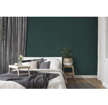 Schlafzimmer mit Bett, Beistelltisch und grüner Wand