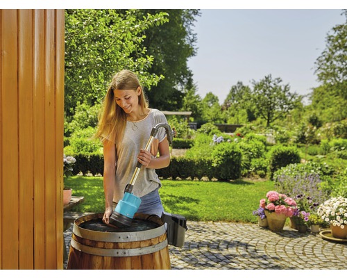 Frau benutzt Regenfasspumpe im Garten