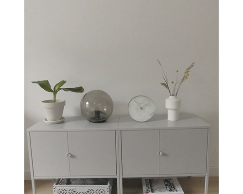 Anrichte mit Zimmerpflanze, Tischleuchte, Uhr und Vase