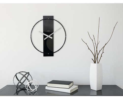 Wanduhr mit Metallzeigern und Dekoration auf einer Kommode