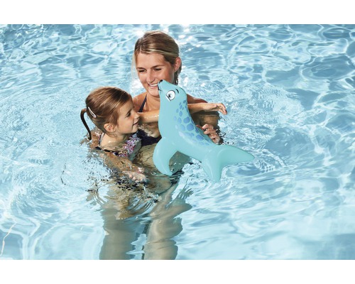 Mutter und Tochter schwimmen mit einer aufblasbaren Robbe im Pool.