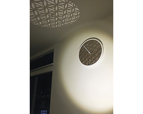 Dekorative Wanduhr mit geometrischem Muster und Lichteffekt an der Decke