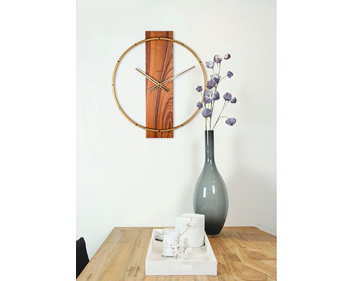 Wanduhr mit Holzdetails und goldenen Akzenten über einem Holztisch mit Dekorationen.