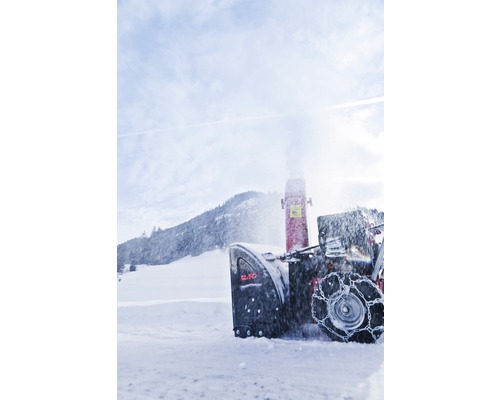Schneefräse im Einsatz vor schneebedeckter Landschaft