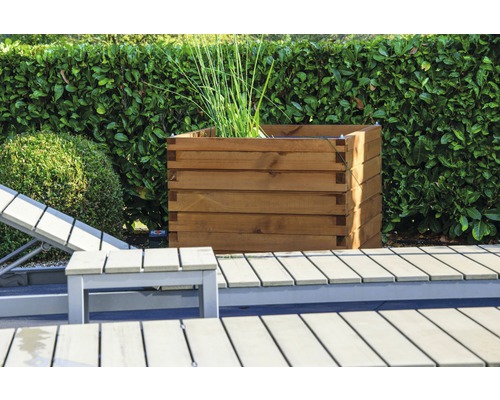 Quadratischer Pflanzkasten aus Holz im Garten neben einer Sonnenliege