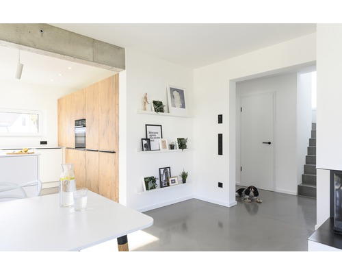 Heller Wohnraum mit offener Küche, Esstisch und Dekoration an der Wand