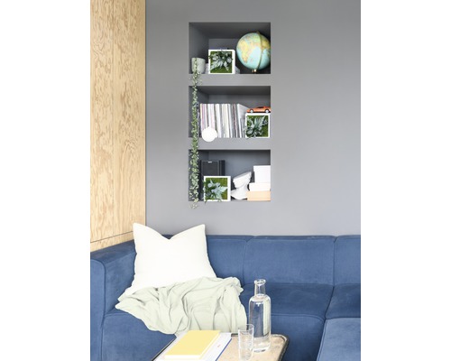 Wohnzimmer mit blauem Sofa, Wandregal und dekorativen Elementen für Wohnraumgestaltung