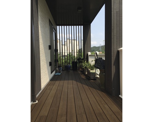 Überdachter Balkon mit Holzterrasse, Pflanzen und Blick auf die Stadt.