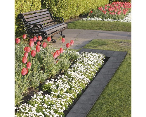 Gartenszene mit Rasen, Blumen und einer Beeteinfassung aus Stein