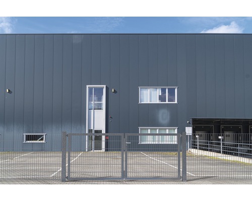 Außenansicht eines Gebäudes mit Metallfassade, Fenstern und einem Tor