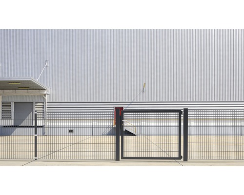 Außenansicht eines Industriegebäudes mit Metallfassade und Zaun