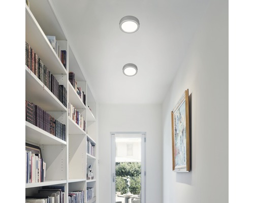 Zwei runde Deckenleuchten in einem hellen Flur mit Bücherregal