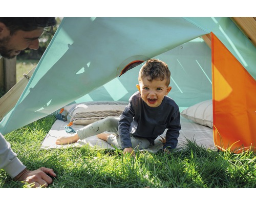 Kind spielt in einem Outdoor-Spielzelt auf einer Wiese.