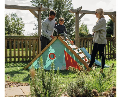 Familie spielt im Garten auf einem hölzernen Klettergerüst mit Rutsche und Zelt