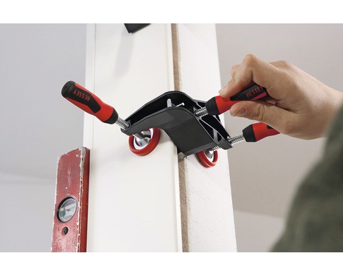 Eine Person fixiert mit einer Winkelspannzwinge von Bessey ein Werkstück.