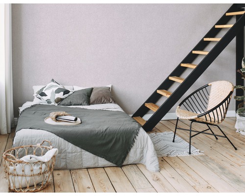 Schlafzimmer mit Bett, Leiter, Sessel und Wäschekorb auf Holzboden