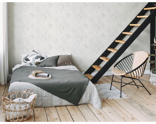 Schlafzimmer mit Bett, Leiter, Sessel und Wäschekorb auf Holzboden
