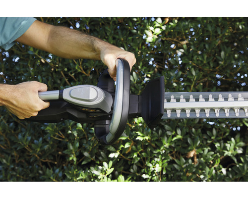 Person bedient eine Heckenschere zum Schneiden von Hecken.