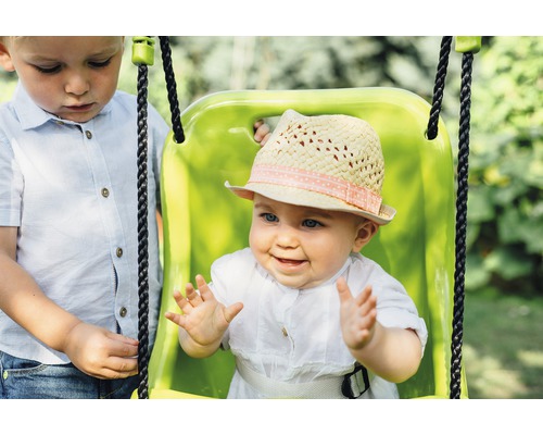 Baby in einer Schaukel mit Hut, daneben ein Kind