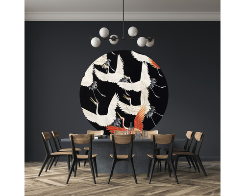 Esszimmer mit Esstisch, Stühlen, Deckenleuchte und runder Wanddekoration mit Kranichmotiven.