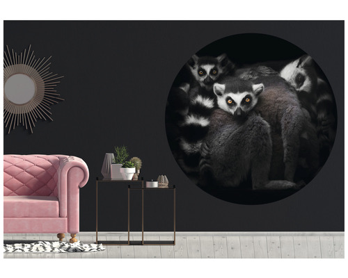 Wohnzimmer mit pinkem Sofa, Beistelltischen und einer Wand mit einem großen, runden Wandtattoo, das Lemuren zeigt