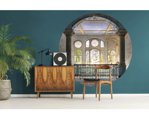 Wohnraum mit einem Vintage-Schrank, einer Zimmerpflanze und einer Wanddekoration mit Architekturelementen.