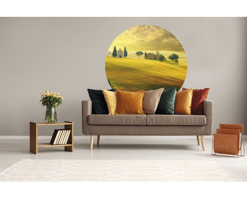 Wohnzimmer mit grauer Couch, Kissen in verschiedenen Farben, Wandtattoo mit Landschaftsmotiv, Holztisch mit Vase und Zeitschriftenständer