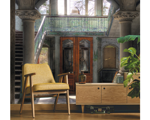 Innenaufnahme eines Raumes mit Sessel, Kommode und Treppe
