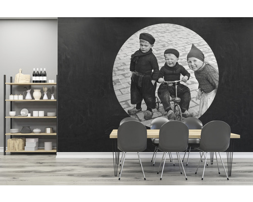 Wohnraum mit Regalen, Esstisch und einer Wandtapete mit einem schwarz-weißen Kinderfoto