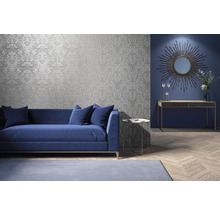 Wohnzimmer mit silberfarbener gemusterter Tapete, Sofa, Tisch und Deko