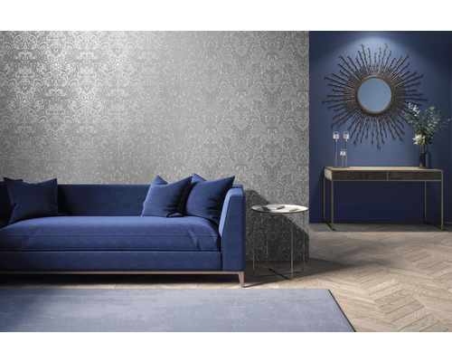 Wohnzimmer mit silberfarbener gemusterter Tapete, Sofa, Tisch und Deko