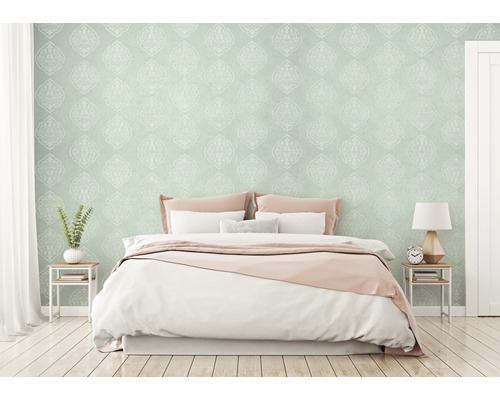 Schlafzimmer mit gemusterter Tapete, Bett und Nachttischen.