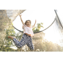 Ein Mädchen springt auf einem Gartentrampolin mit Sicherheitsnetz.