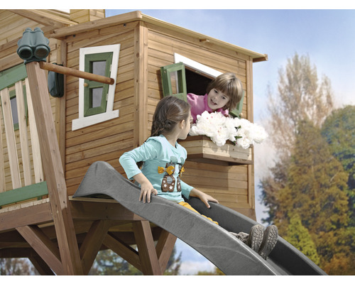 Kinderrutsche an einem Baumhaus mit zwei Kindern, eines auf der Rutsche und eines am Fenster