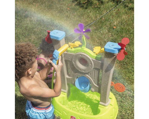 Wasserspieltisch mit Zubehör im Garten mit spielenden Kindern