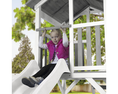 Mädchen auf einer Rutsche in einem Spielturm aus Holz