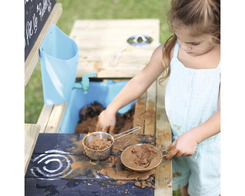 Mädchen spielt mit einer Matschküche im Garten
