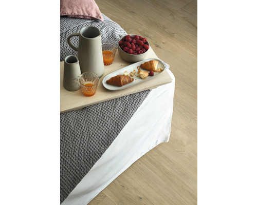 Frühstückstablett mit Krug, Gläsern, Himbeeren und Croissants auf einem Bett