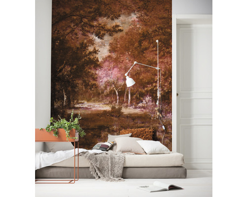 Ein Schlafzimmer mit einer Fototapete, die eine Waldlandschaft zeigt, einem Bett mit Kissen und einer Tagesdecke sowie einer Stehlampe.