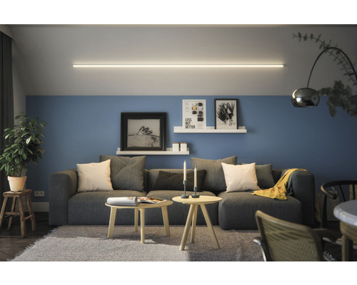 Wohnzimmer mit grauem Sofa, Holztischen, Wandregalen und linearem Deckenlicht
