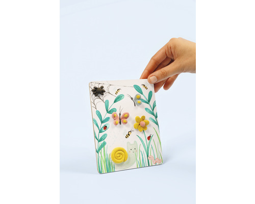 Dekorationstafel mit Gartenmotiven und modellierten Figuren in Kinderhand