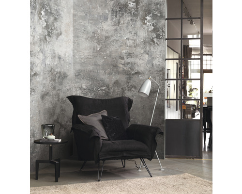 Wohnzimmer mit schwarzem Sessel, Stehlampe und Beistelltisch vor einer Wand mit Putzstruktur