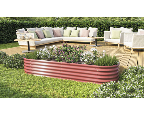 Ein Hochbeet aus Metall mit Pflanzen und Gartenmöbeln im Hintergrund.