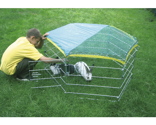 Kind mit Freilaufgehege mit Netzabdeckung und Kaninchen im Garten