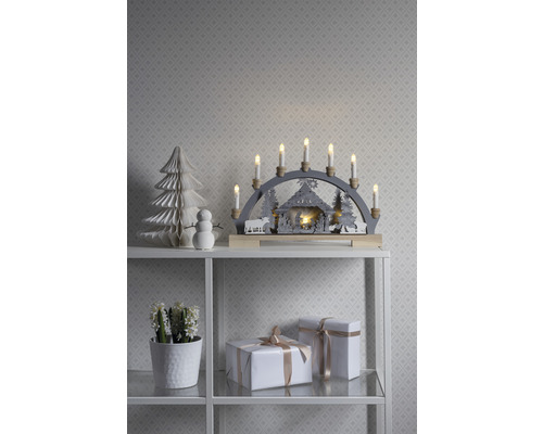 Weihnachtsdekoration mit Lichterbogen, Papierbaum, Schneemann und Geschenken auf einem Regal